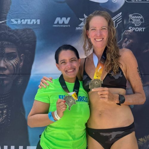 two women triathletes holding medals after swim race